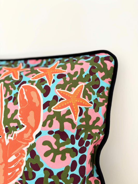 Housse de coussin avec un homard, des étoiles de mer et des coquillages.