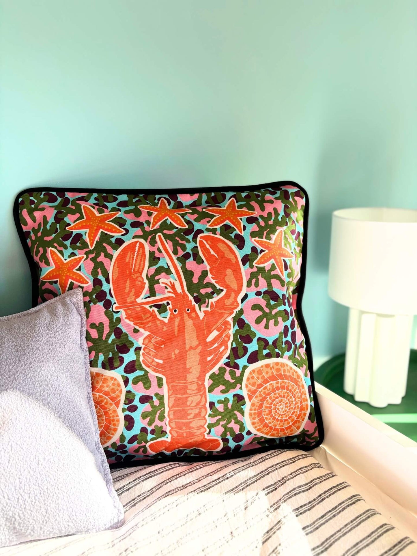 Housse de coussin avec un homard, des étoiles de mer et des coquillages.