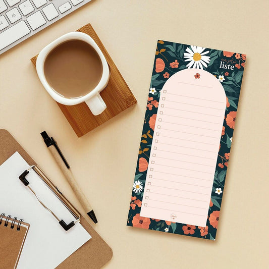 bloc-notes imprimé fleurs avec des lignes et des cases de Maison Joliette, à côté d'un café