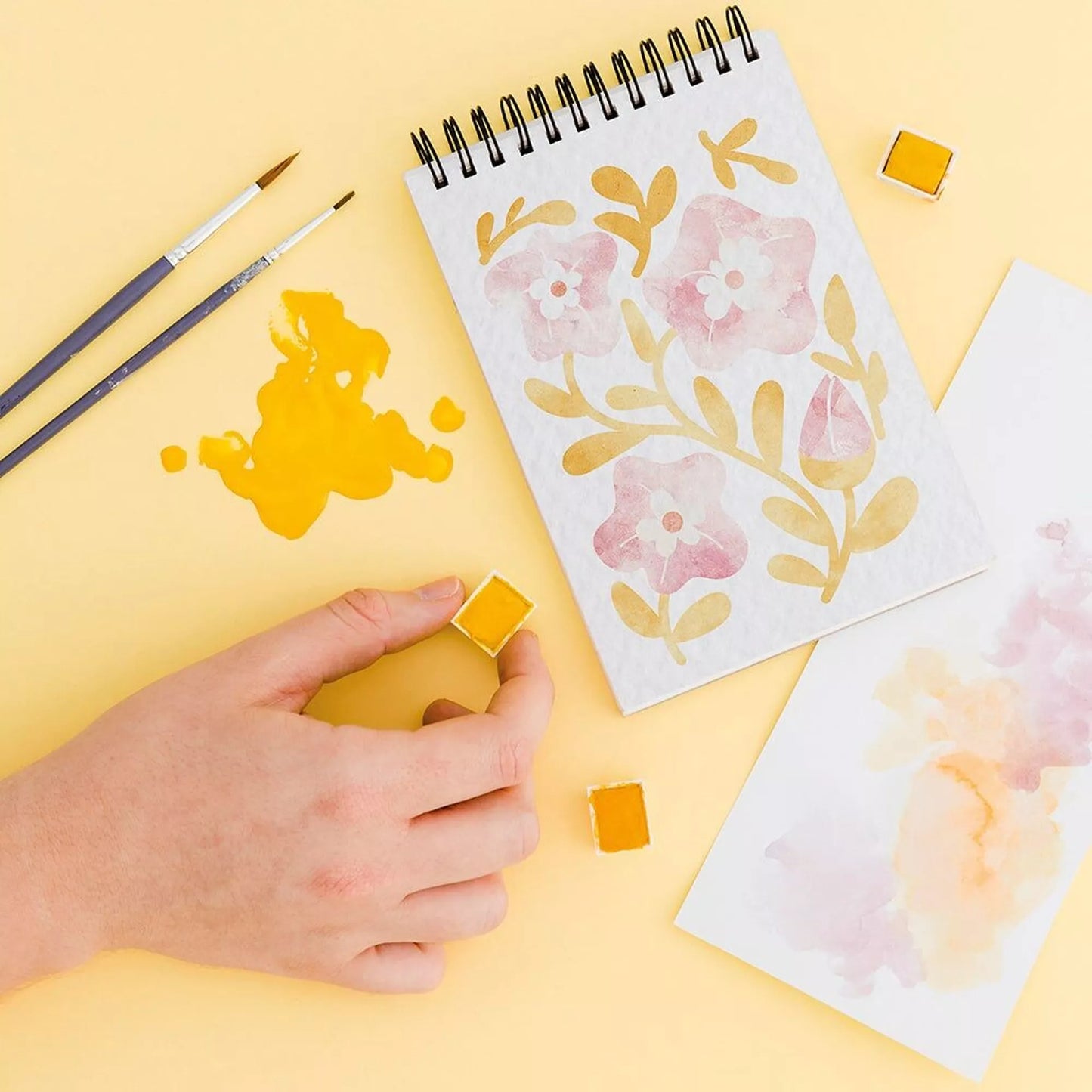 Carnet de coloriages pour adultes avec des fleurs, des pinceaux et de la peinture jaune.