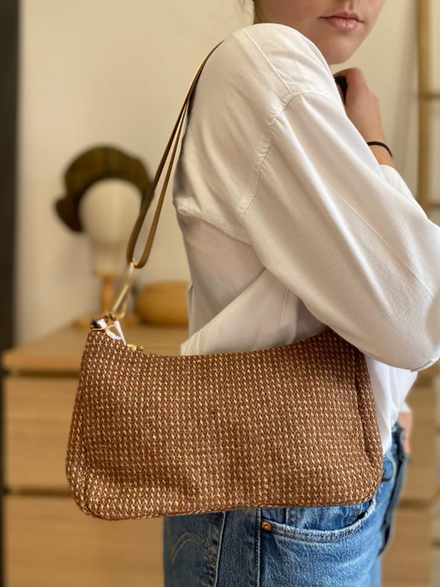 Sac baguette upcyclé en laine marron, porté par une femme avec une chemise blanche.