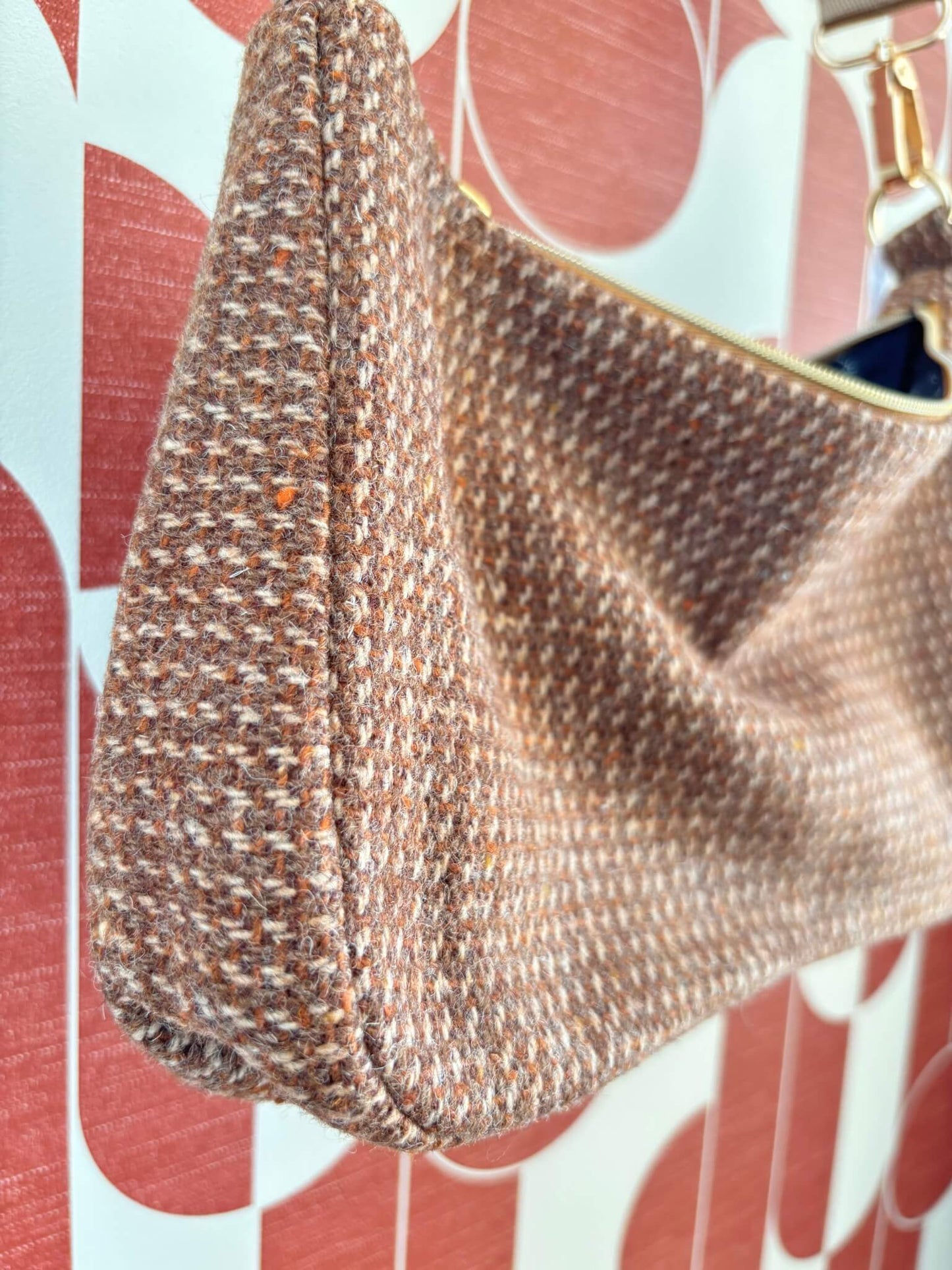 Sac baguette upcyclé en laine marron accroché à une patère dorée.