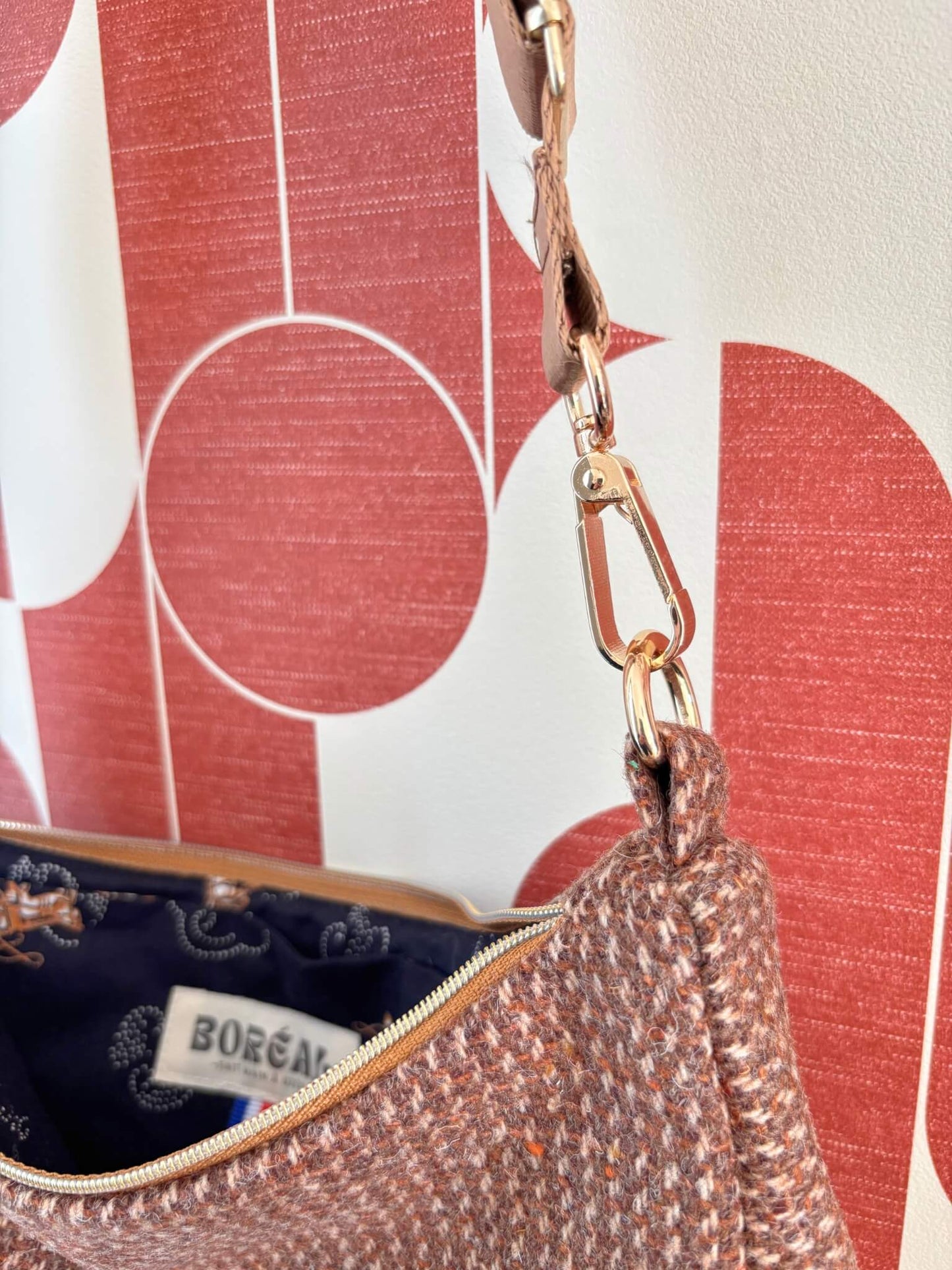 Sac baguette upcyclé en laine marron accroché à une patère dorée.