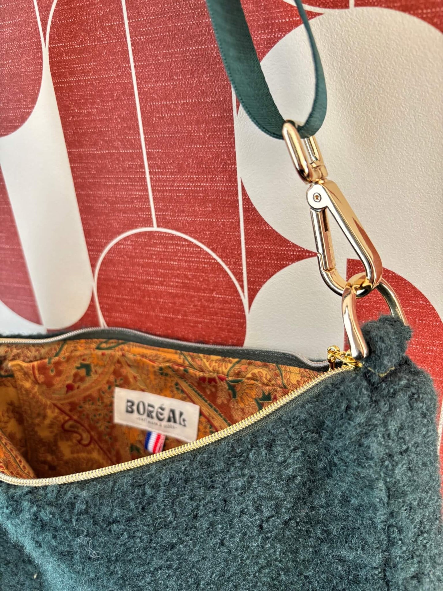 Sac baguette en moumoute verte accroché à une patère dorée.