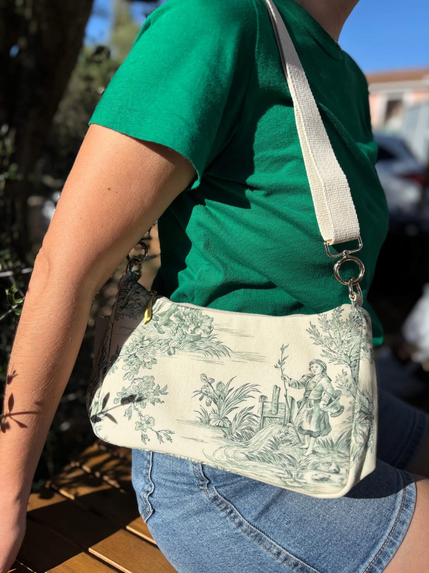 Sac baguette en toile de Jouy verte, avec une sangle beige réglable.