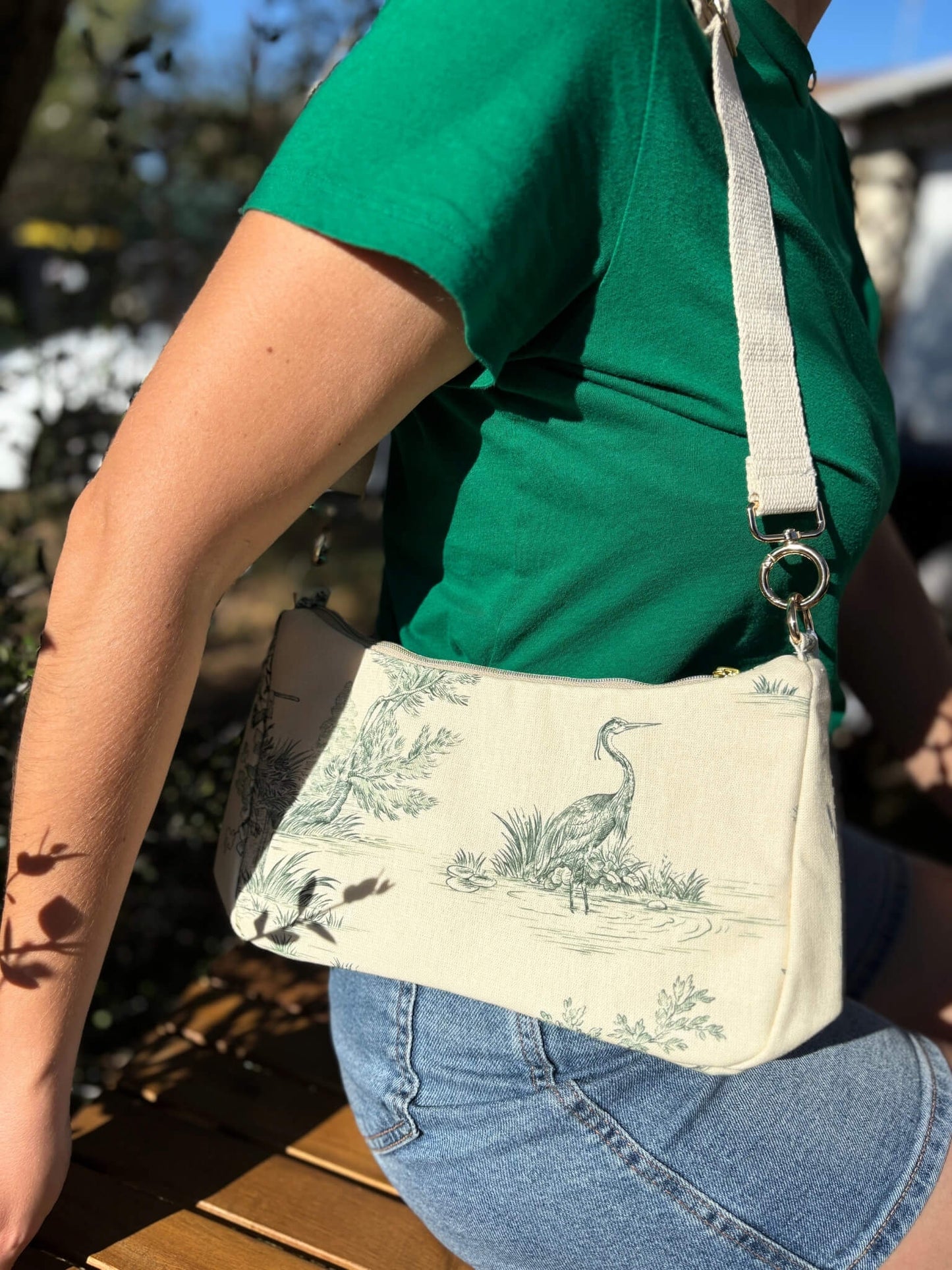 Sac baguette en toile de Jouy verte, avec une sangle beige réglable.