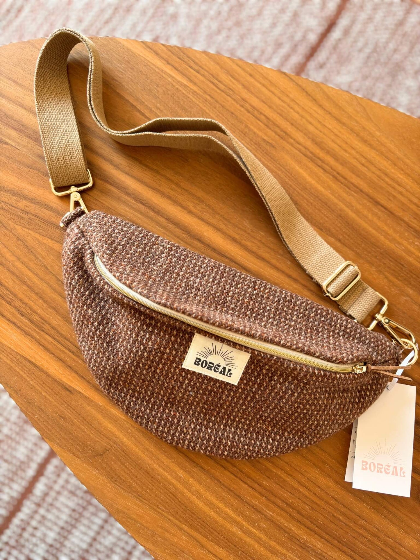 Sac banane marron en laine upcyclée, avec une sangle beige réglable.