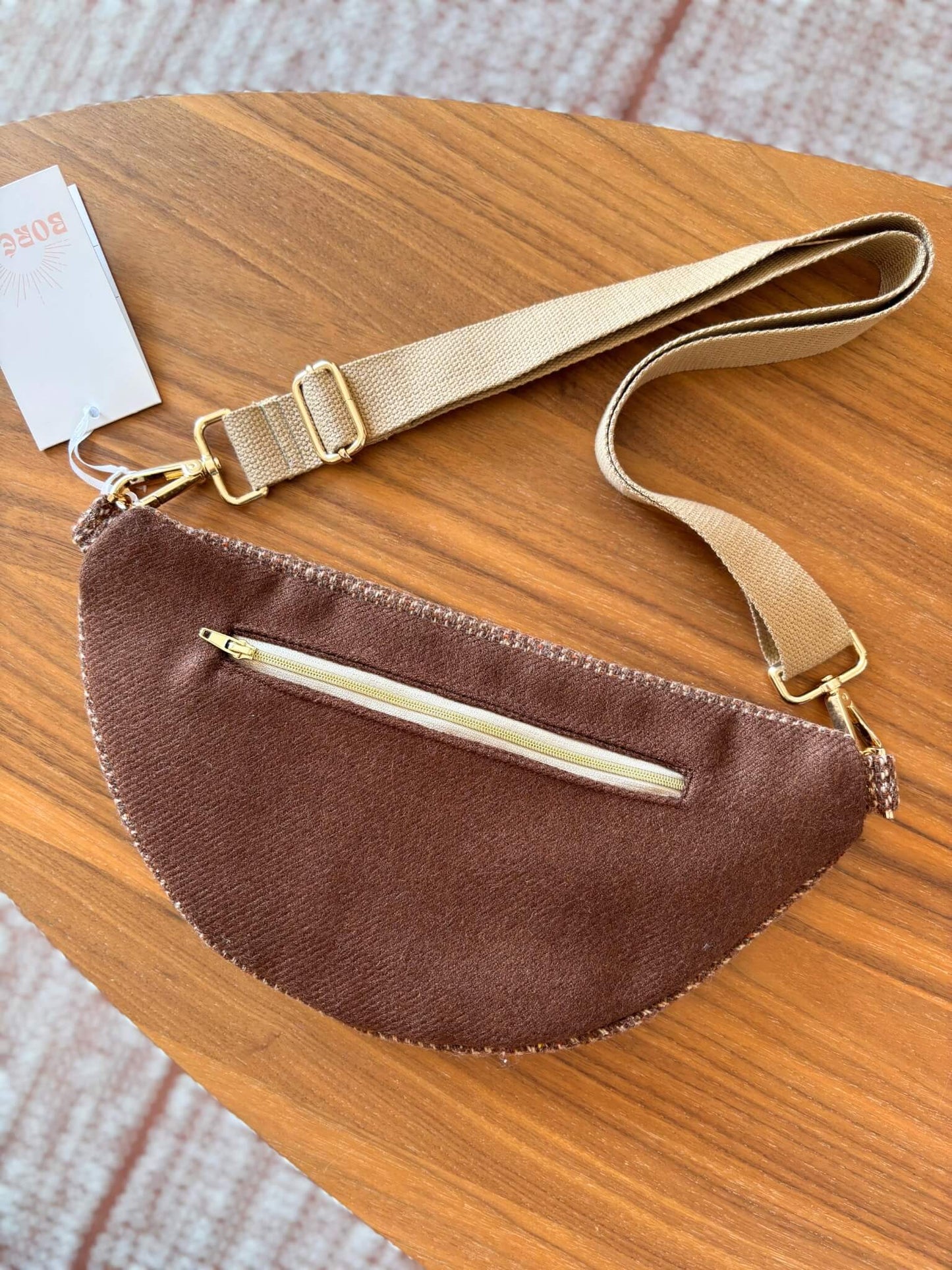 Sac banane marron en laine upcyclée, avec une sangle beige réglable.