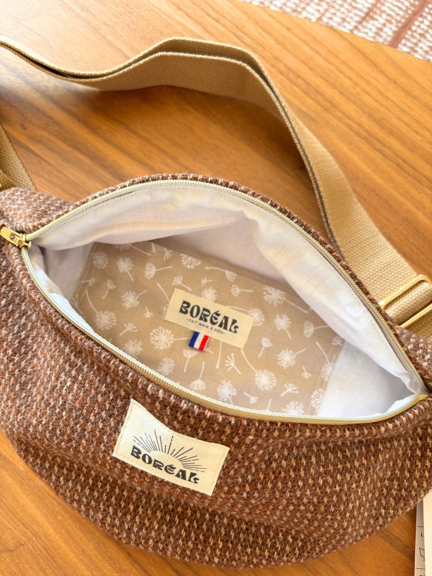 Sac banane marron en laine upcyclée, avec une sangle beige réglable.