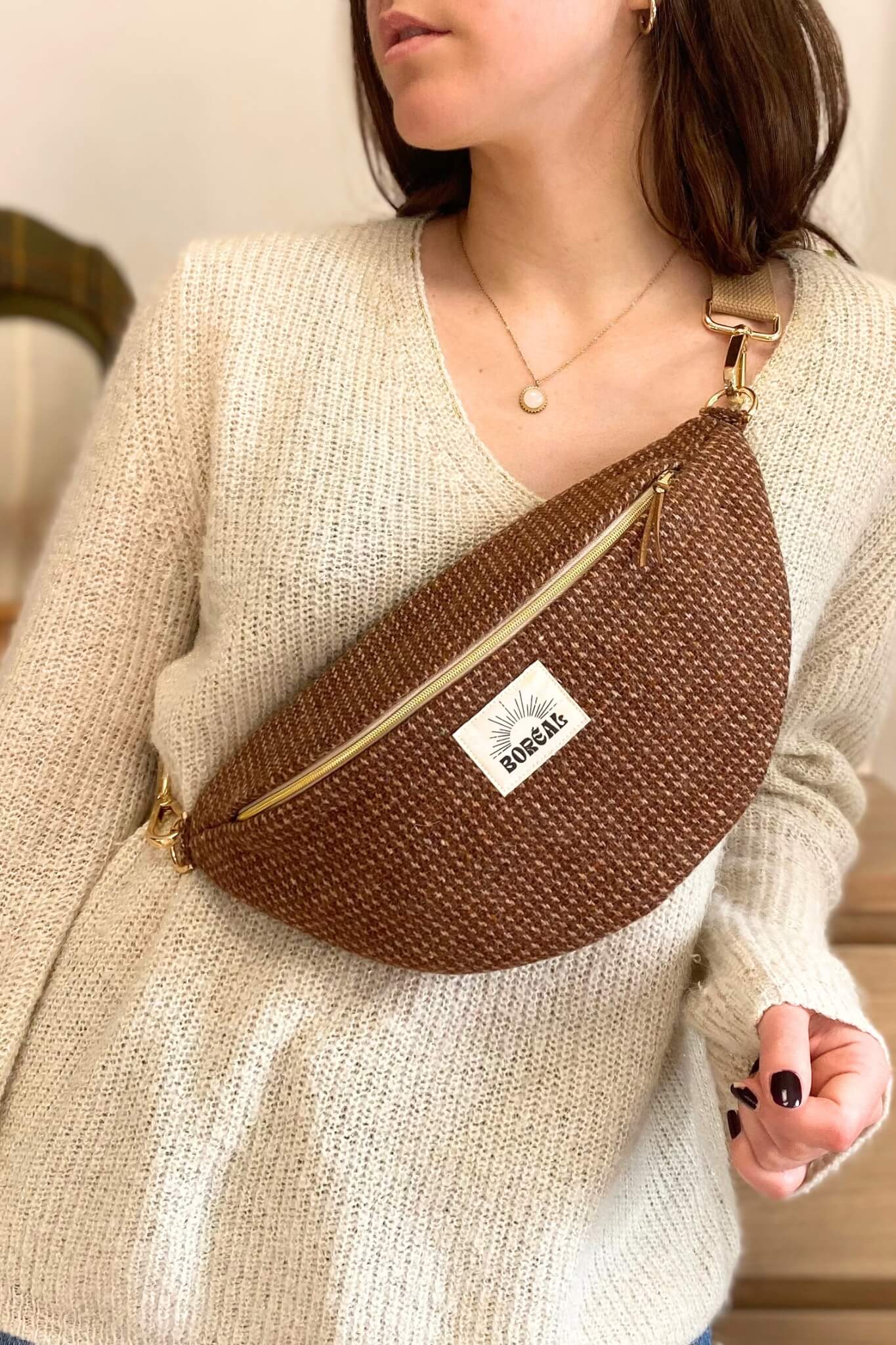 Sac banane marron et doré, en laine, porté par une femme