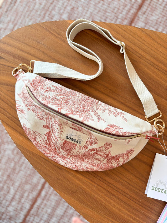 Sac banane en toile de Jouy rouge, avec une sangle beige réglable.