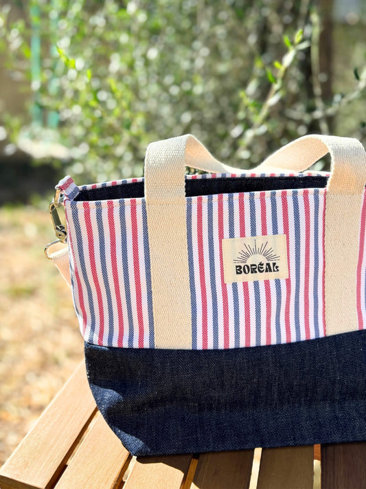 Sac à bandoulière en jean et coton rayé, avec une sangle beige réglable.