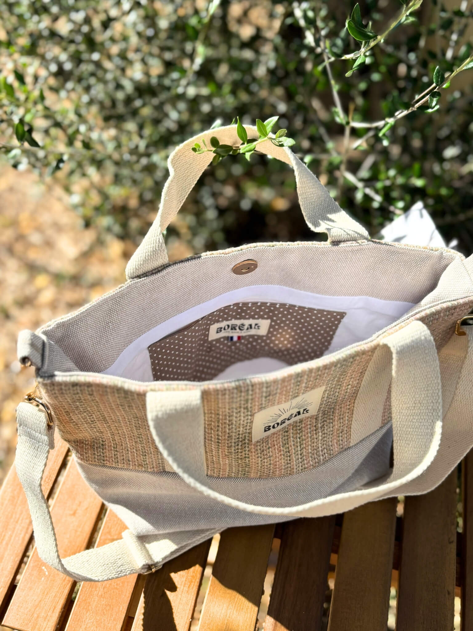 Sac à bandoulière en laine beige, avec une sangle beige réglable.