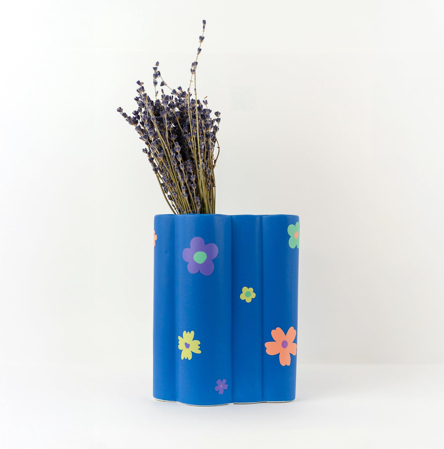 Stickers fleurs colorées, collés sur un vase bleu.