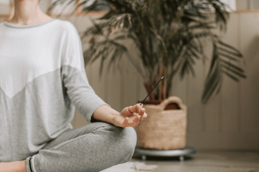femme qui fait du yoga avec un bâton d'encens dans les mains
