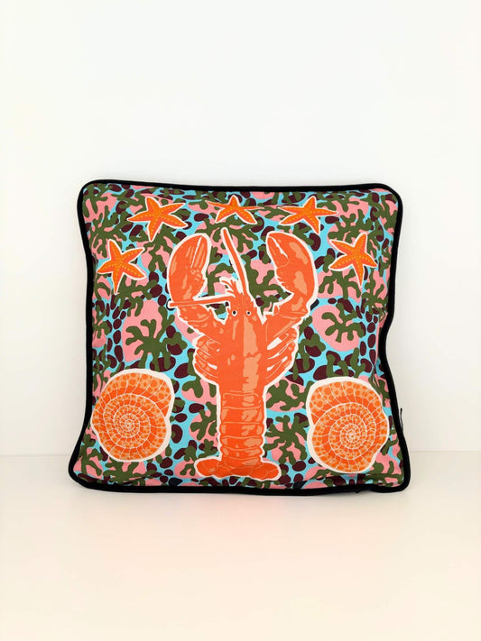 Housse de coussin avec un homard, des étoiles de mer et des coquillages.