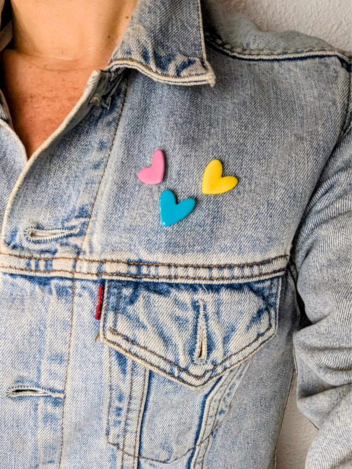 Ensemble de petits pin's en forme de cœur portés sur une veste en jean levi's, fabrication artisanale et française