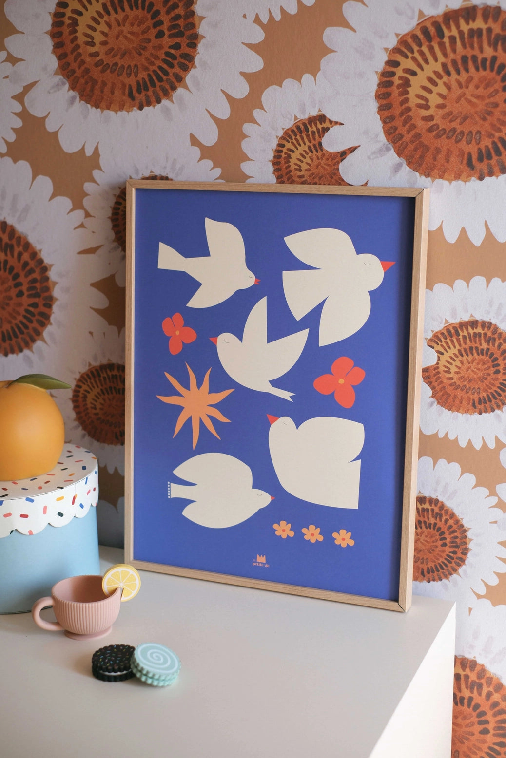 Affiche murale décorative bleue avec des oiseaux, posée sur un meuble blanc.