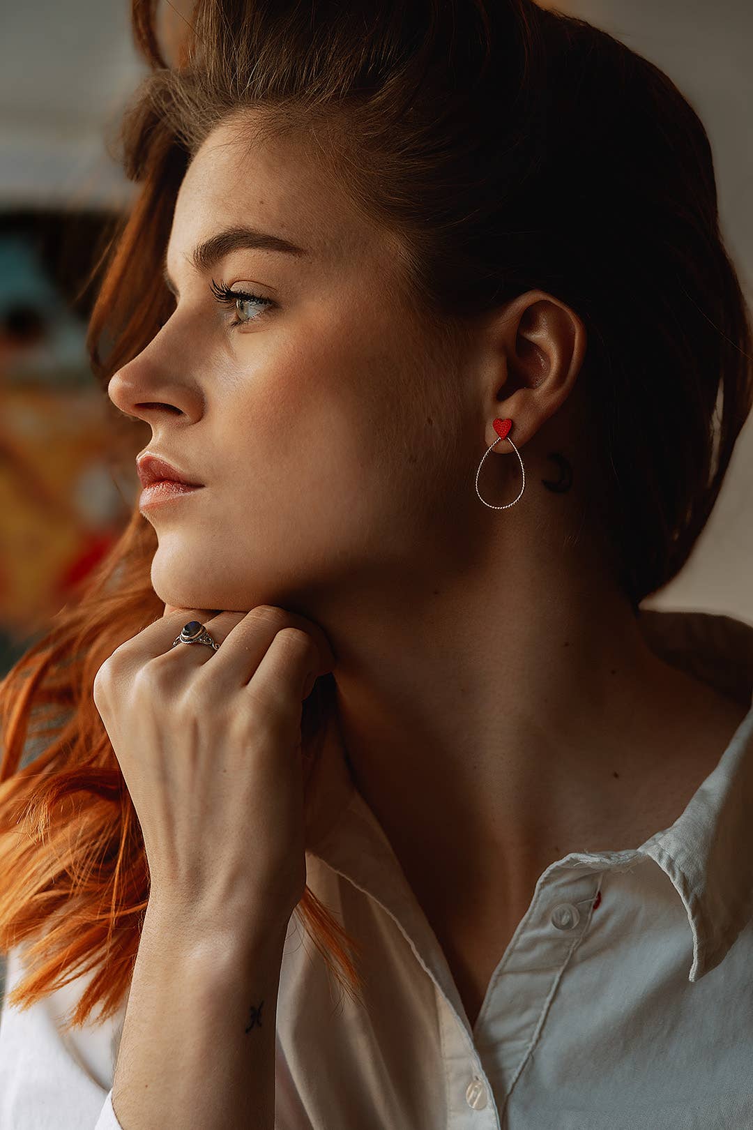 Boucles d'oreilles avec cœurs rouges en cuir upcyclé amovibles, portées par une femme rousse