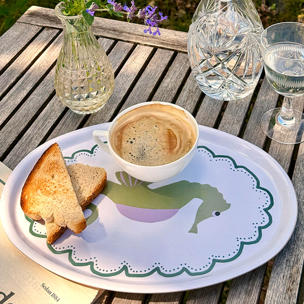 Plateau ovale en bois avec un hippocampe illustré, un café et des tartines sont posés dessus.