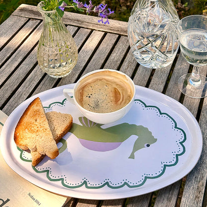 Plateau ovale en bois avec un hippocampe illustré, un café et des tartines sont posés dessus.
