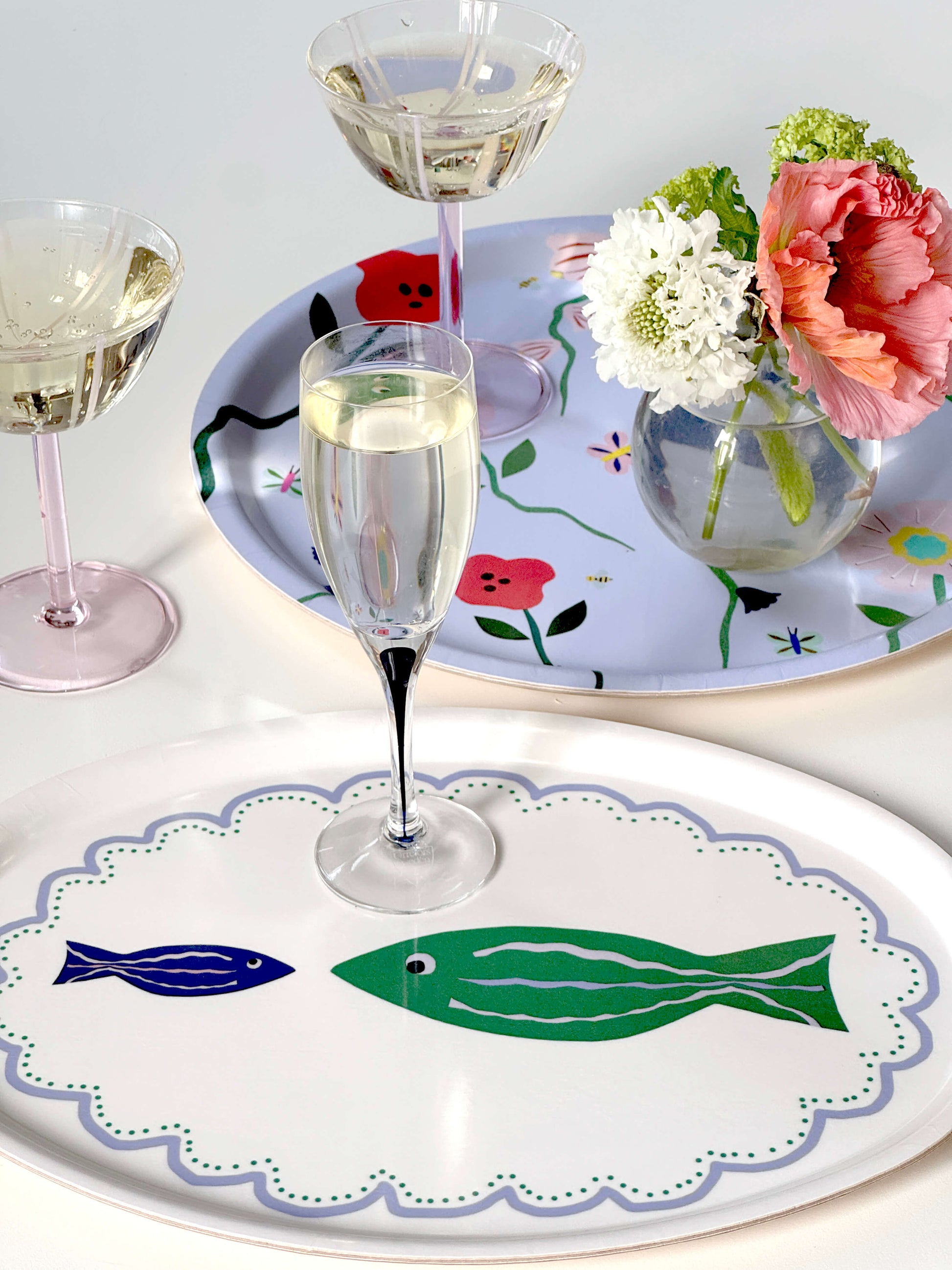 Plateau ovale en bois avec des poissons illustrés, et une coupe de champagne posée dessus.