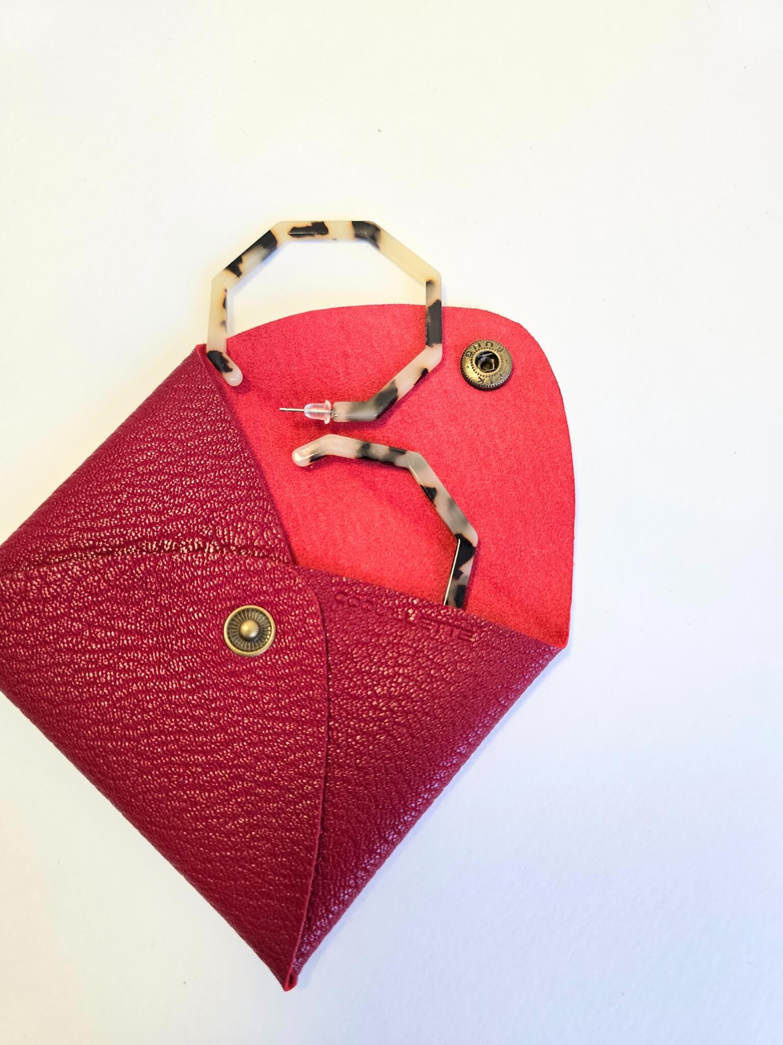 Porte-monnaie en cuir rouge avec des boucles d'oreilles à l'intérieur.