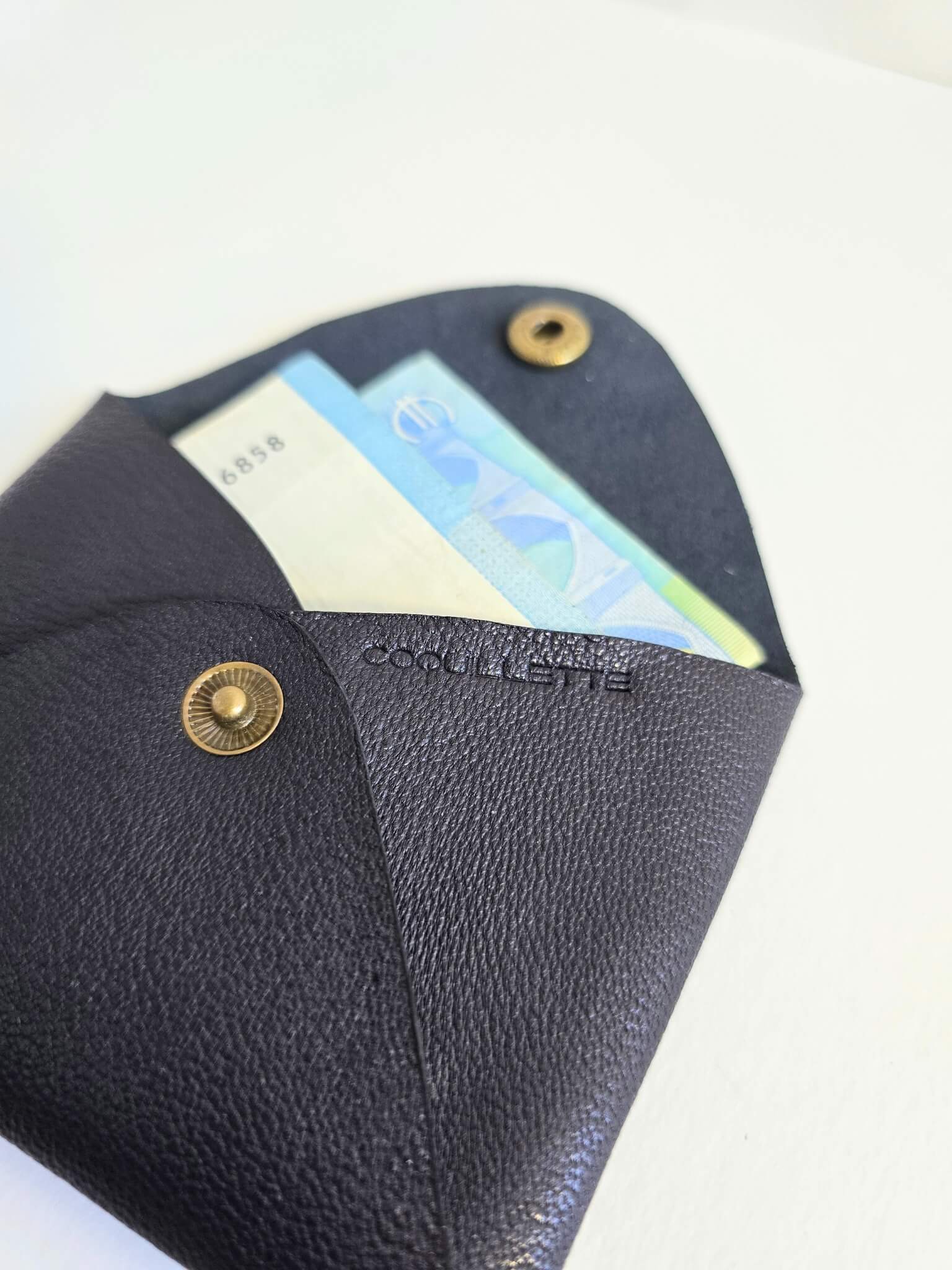 Porte-monnaie en cuir noir avec des billets à l'intérieur.