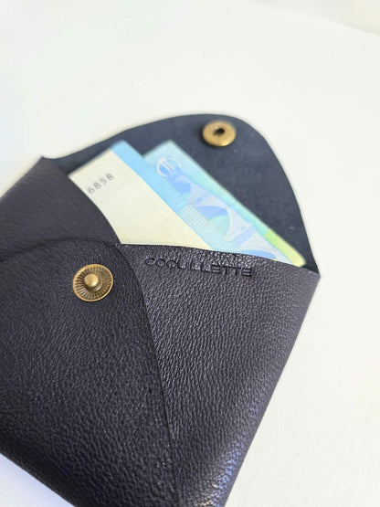 Porte-monnaie en cuir noir avec des billets à l'intérieur.