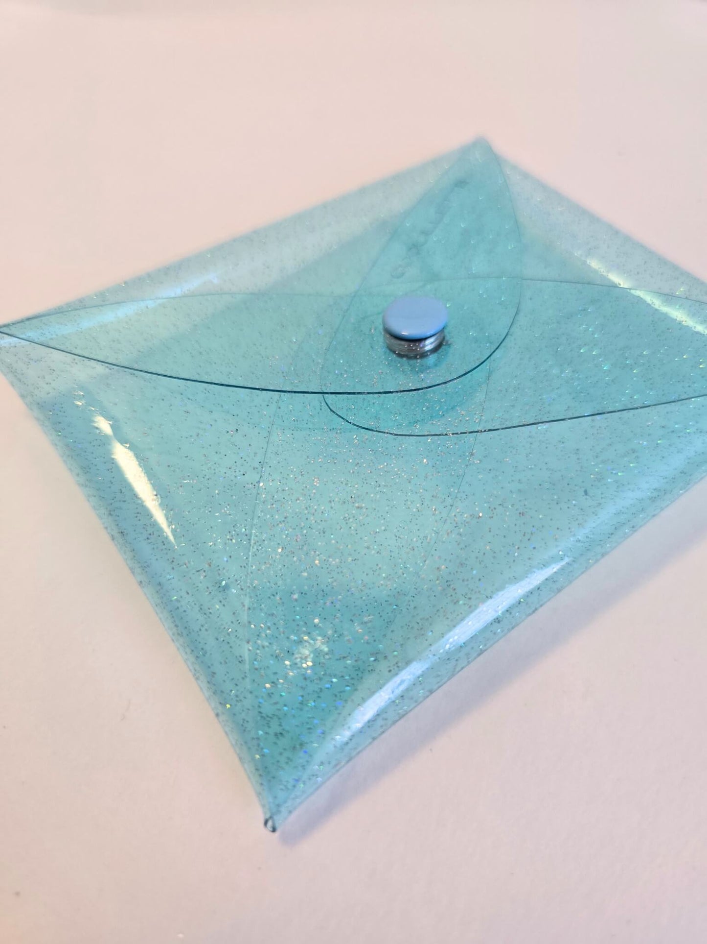 Porte monnaie transparent en vinyle bleu irisé.