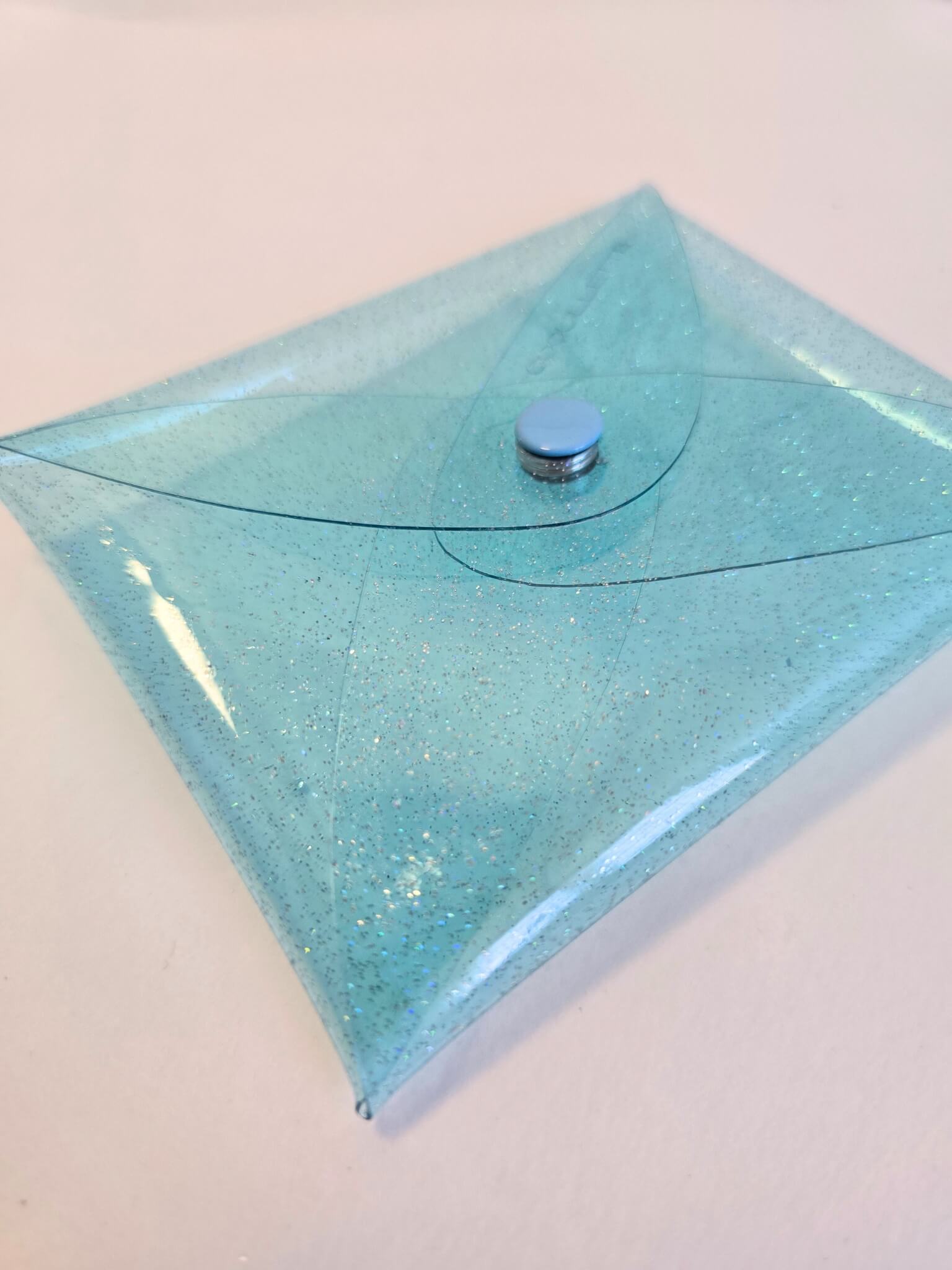 Porte monnaie transparent en vinyle bleu irisé.