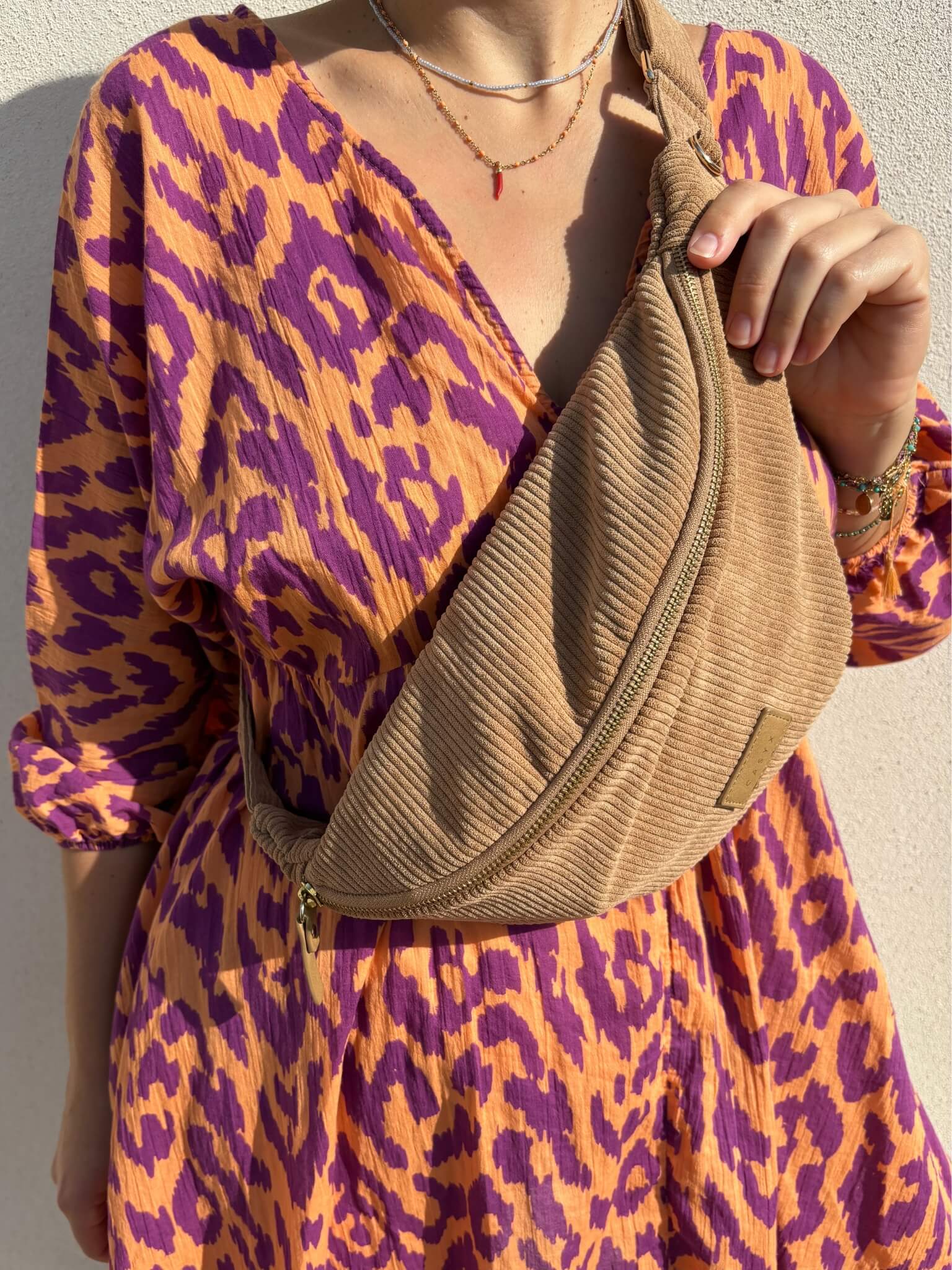 sac banane velours côtelé camel porté sur une robe violette et orange