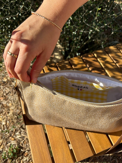 Sac baguette beige en coton, avec une sangle mordorée réglable.