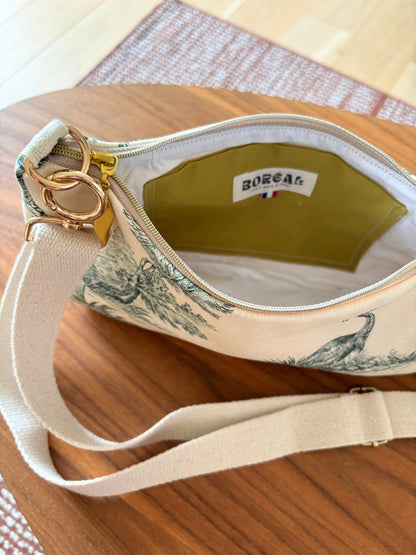 Sac baguette en toile de Jouy verte, avec une sangle beige réglable.