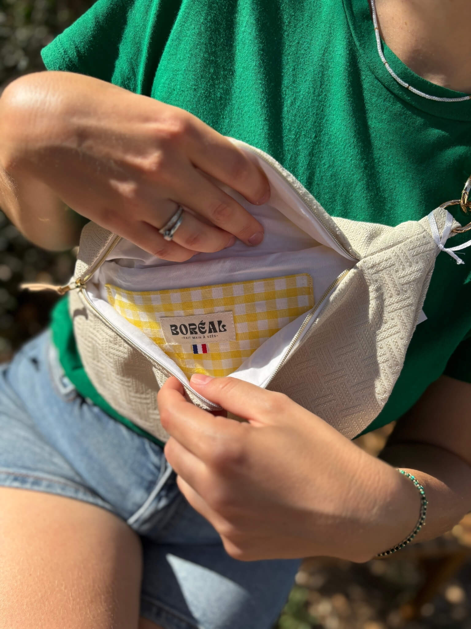 Sac banane écru en coton, avec une sangle beige réglable.