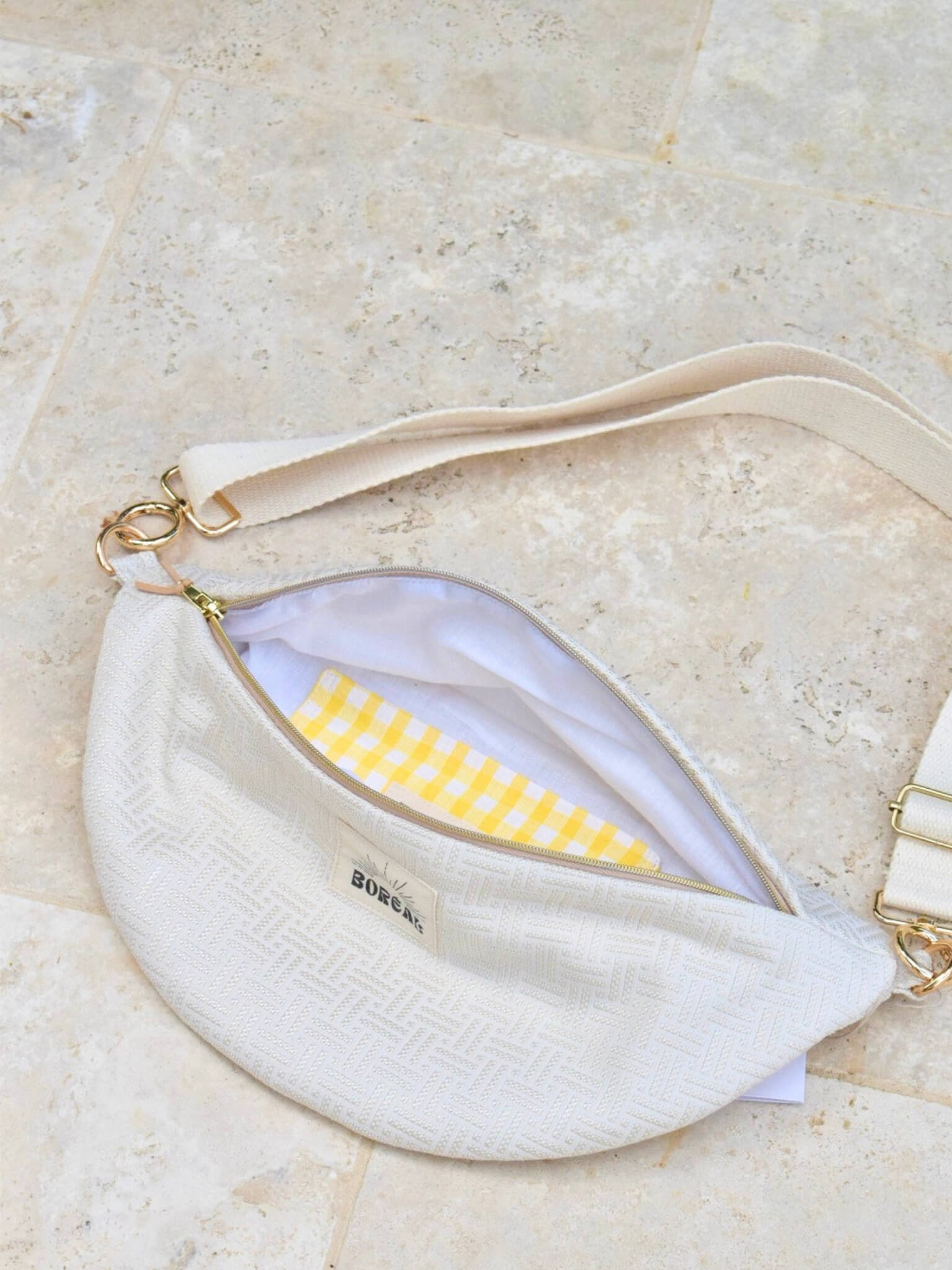 Sac banane écru en coton, avec une sangle beige réglable.