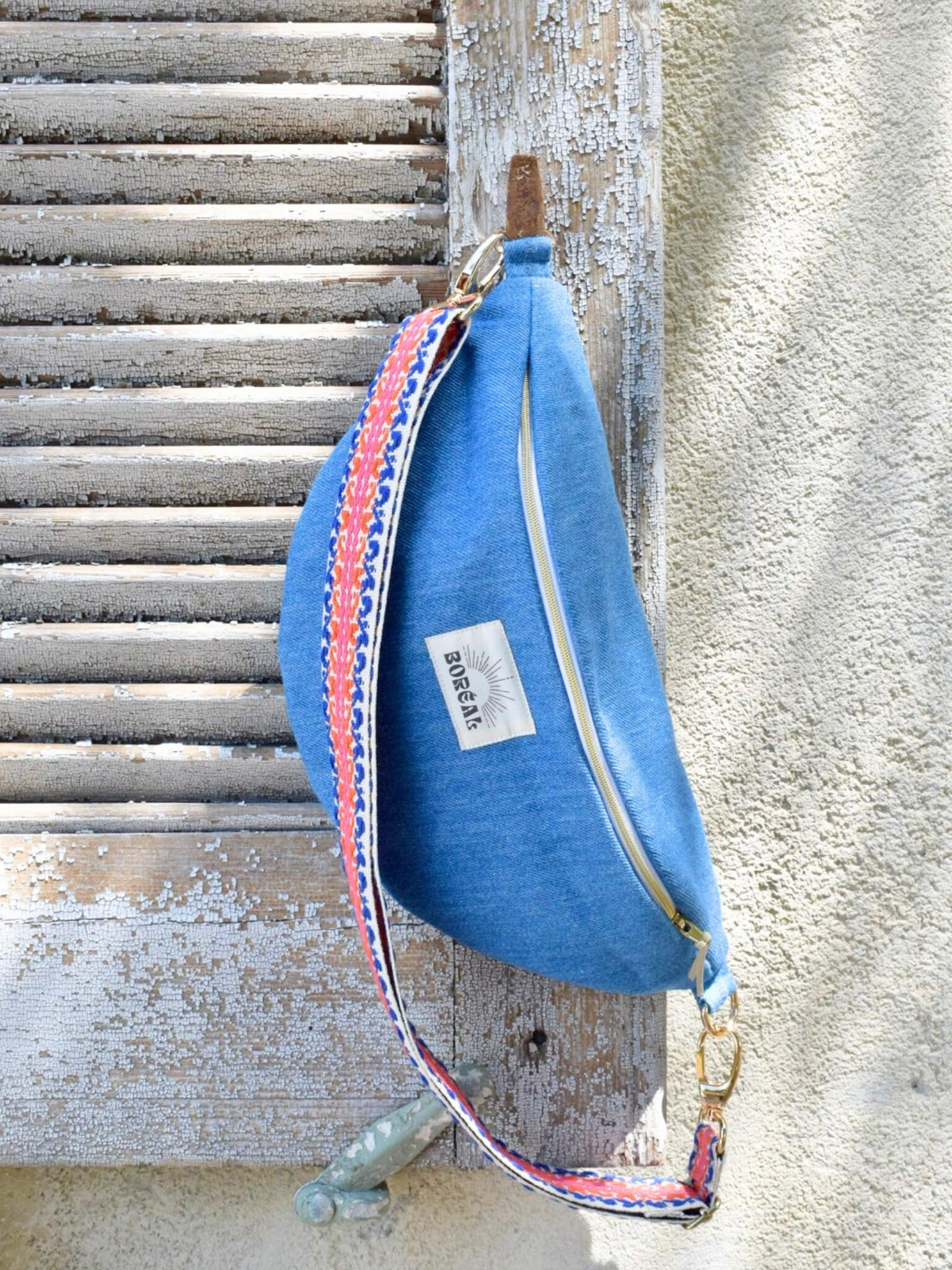 Sac banane bleu en jean, avec une sangle colorée réglable.