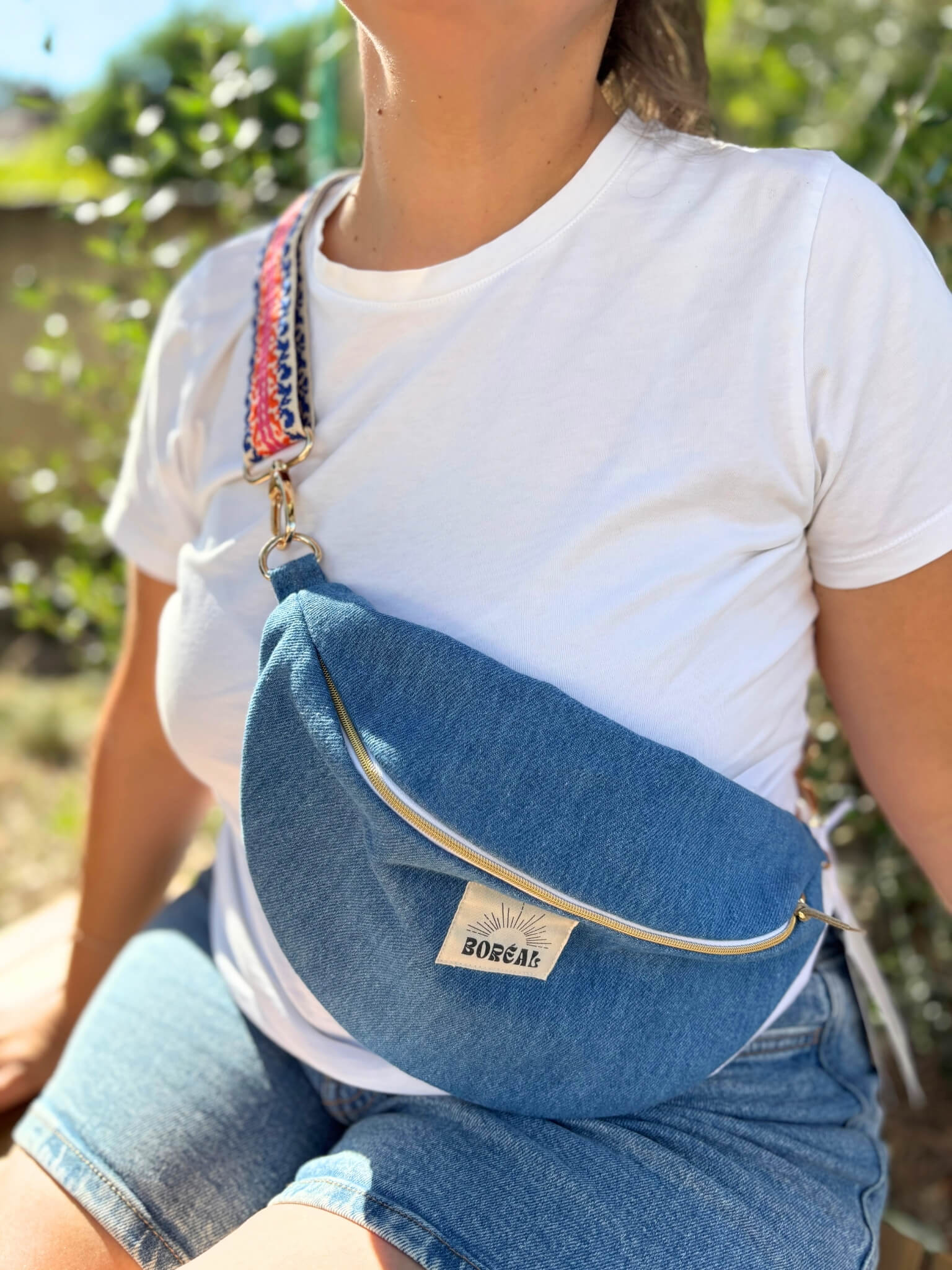 Sac banane bleu en jean, avec une sangle colorée réglable.