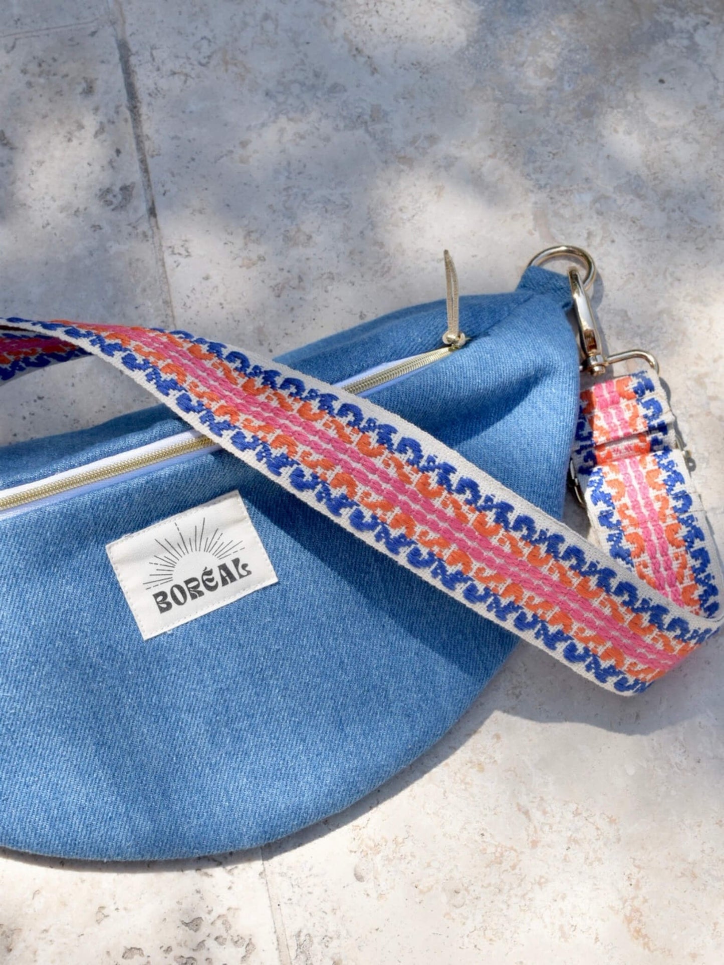 Sac banane bleu en jean, avec une sangle colorée réglable.