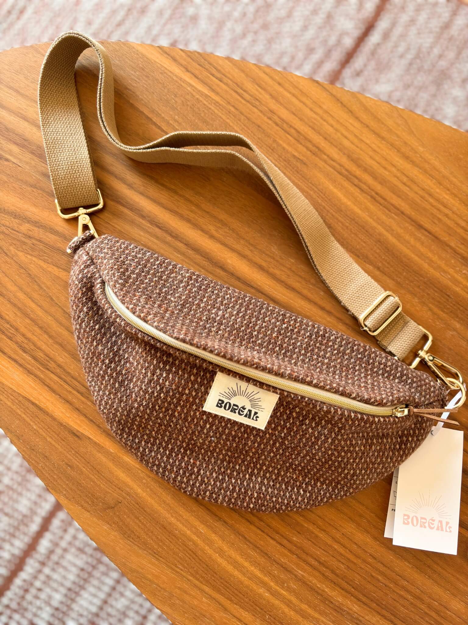 Sac banane marron en laine upcyclée, avec une sangle beige réglable.