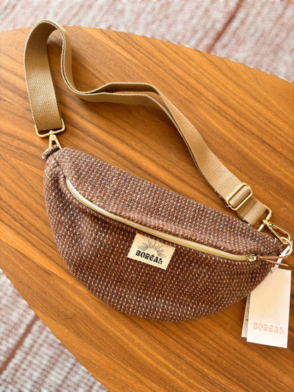 Sac banane marron en laine upcyclée, avec une sangle beige réglable.