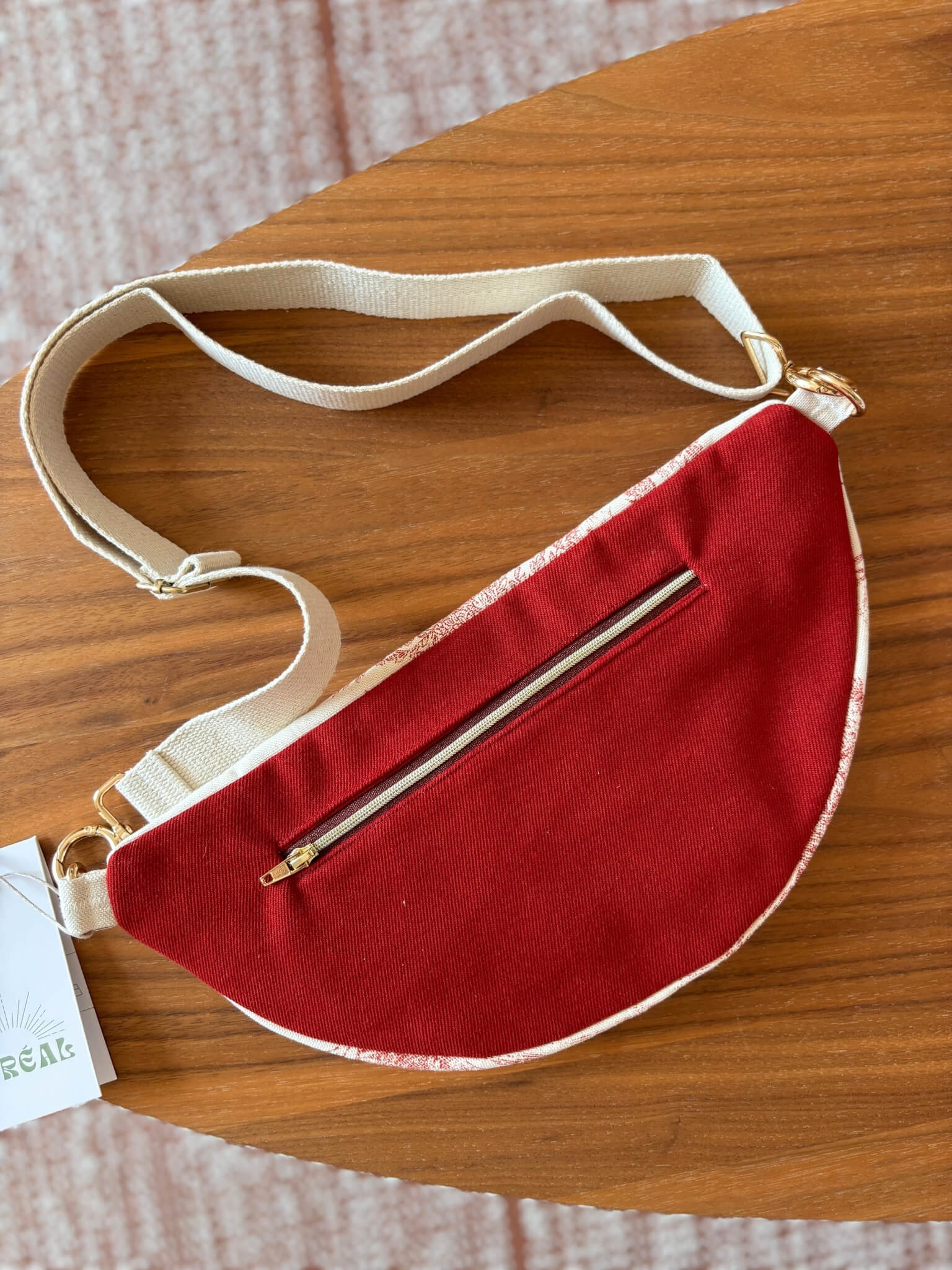 Sac banane en toile de Jouy rouge, avec une sangle beige réglable.