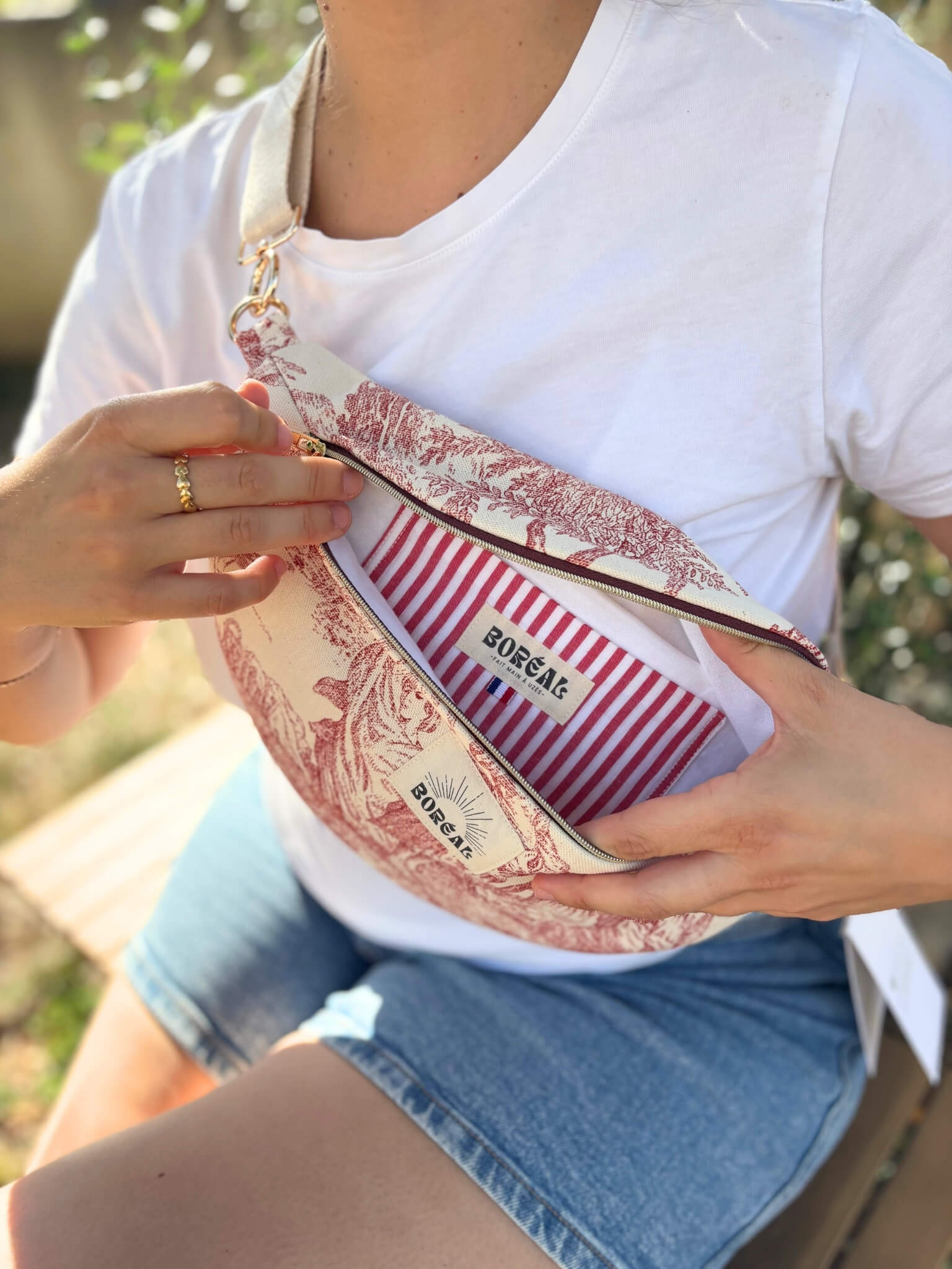 Sac banane en toile de Jouy rouge, avec une sangle beige réglable.