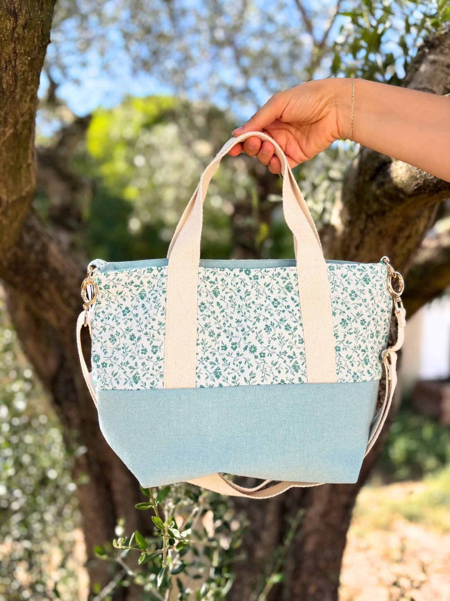 Sac à bandoulière en coton bleu fleuri, avec une sangle beige réglable.