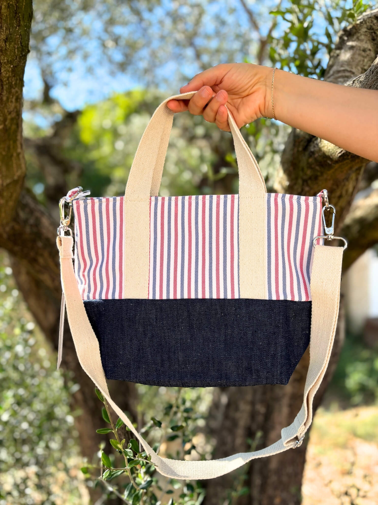 Sac à bandoulière en jean et coton rayé, avec une sangle beige réglable.