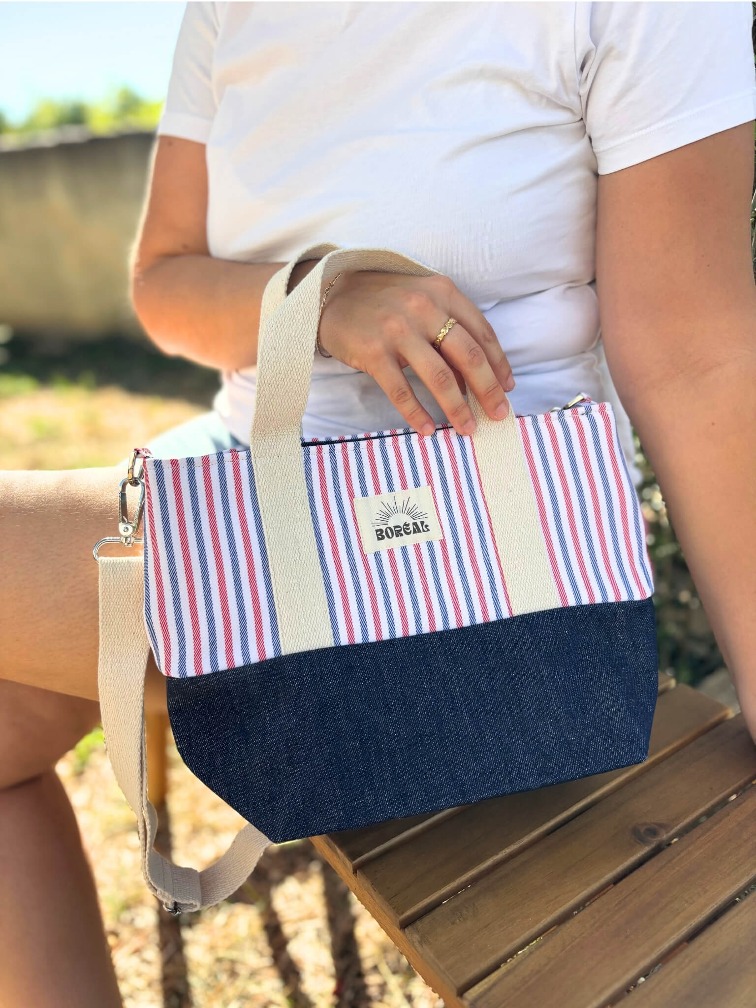 Sac à bandoulière en jean et coton rayé, avec une sangle beige réglable.
