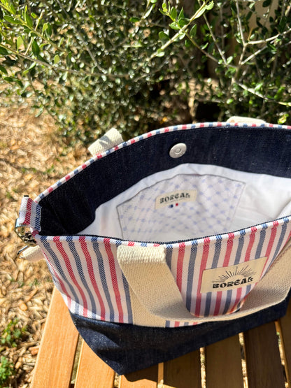 Sac à bandoulière en jean et coton rayé, avec une sangle beige réglable.