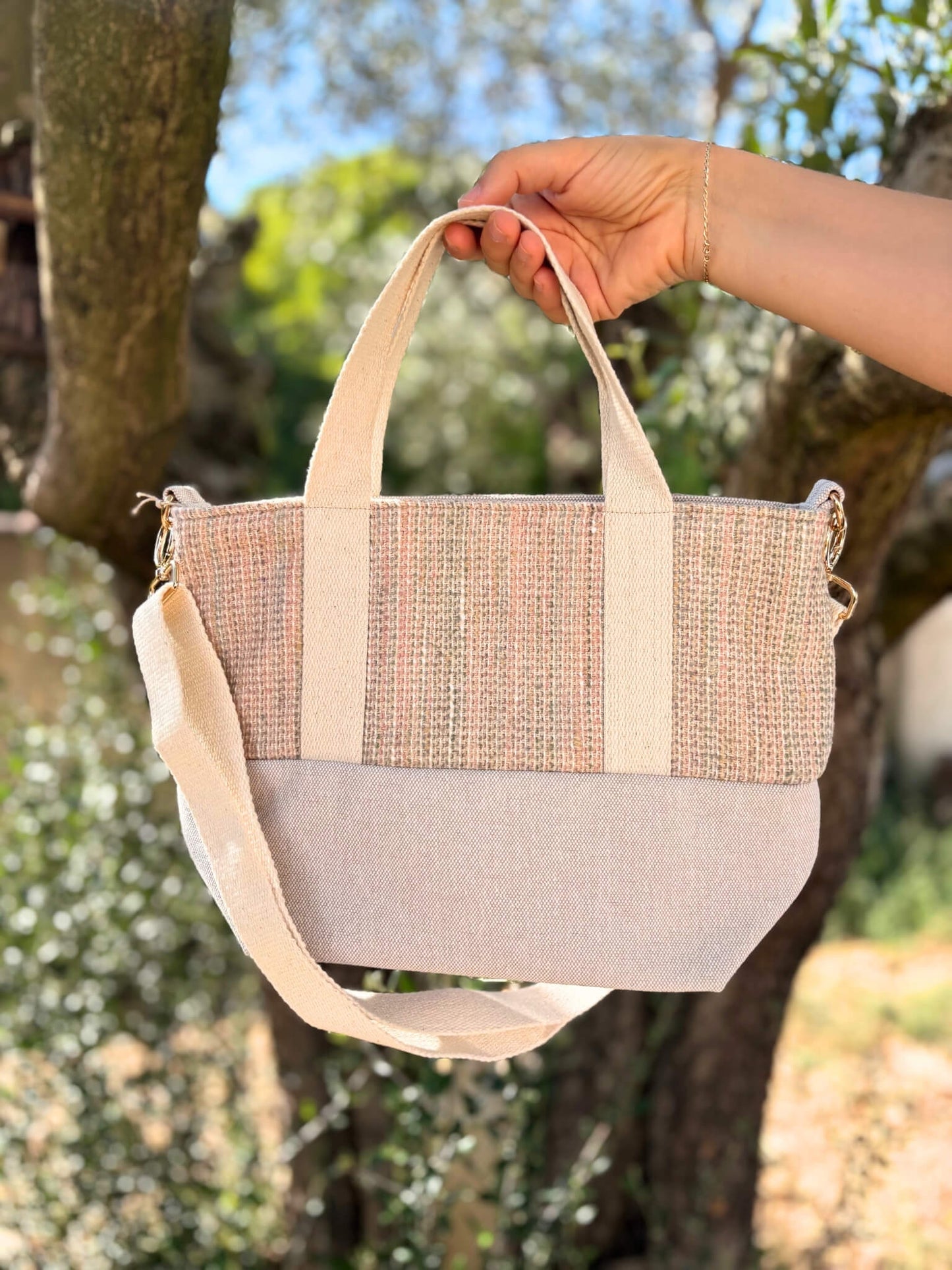 Sac à bandoulière en laine beige, avec une sangle beige réglable.