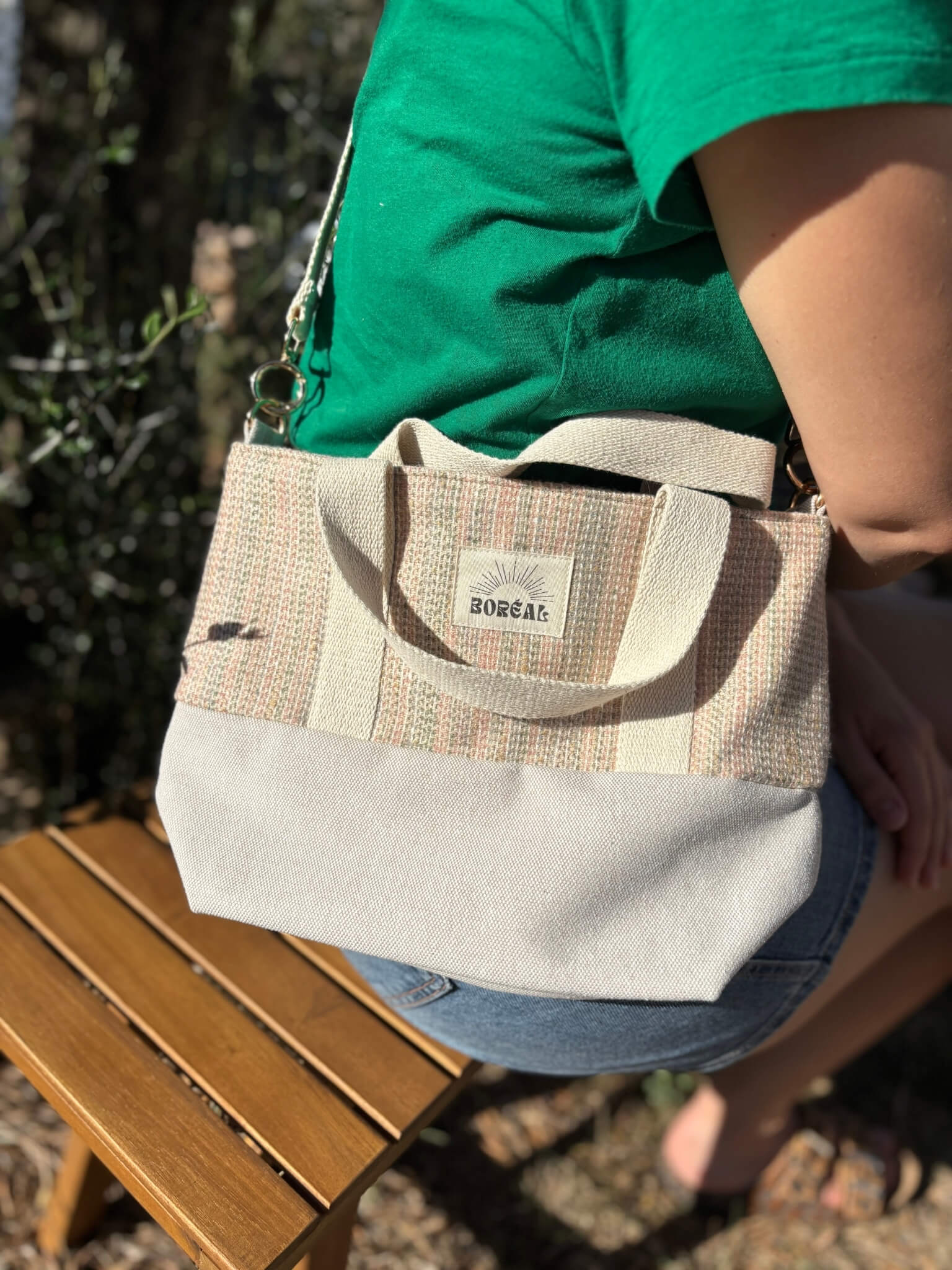 Sac à bandoulière en laine beige, avec une sangle beige réglable.