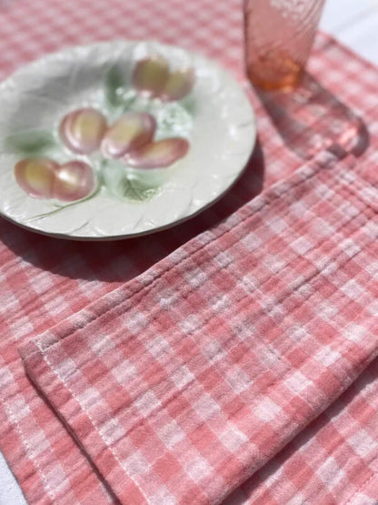 serviette de table rose en gaze de coton à côté d'une assiette